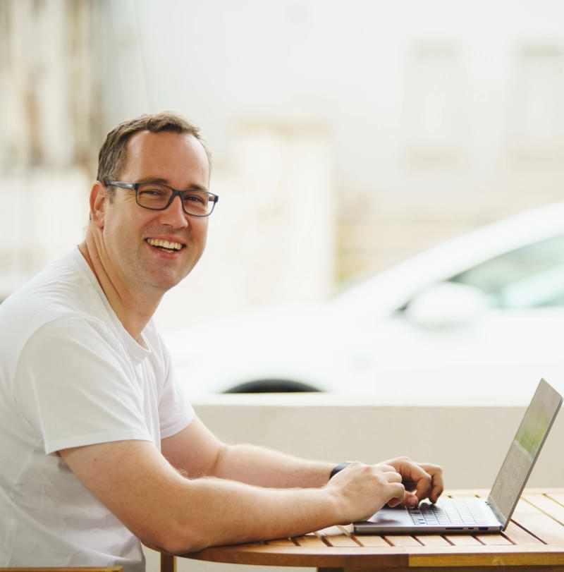 Image of a person sitting in front of a laptop and smilling